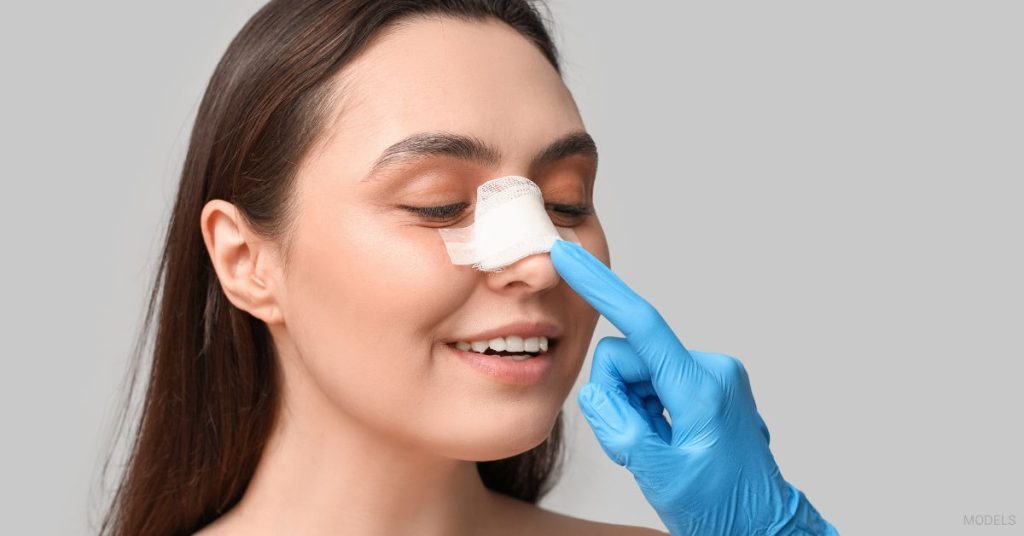Woman with a bandaged nose being examined by a doctor. (Model)